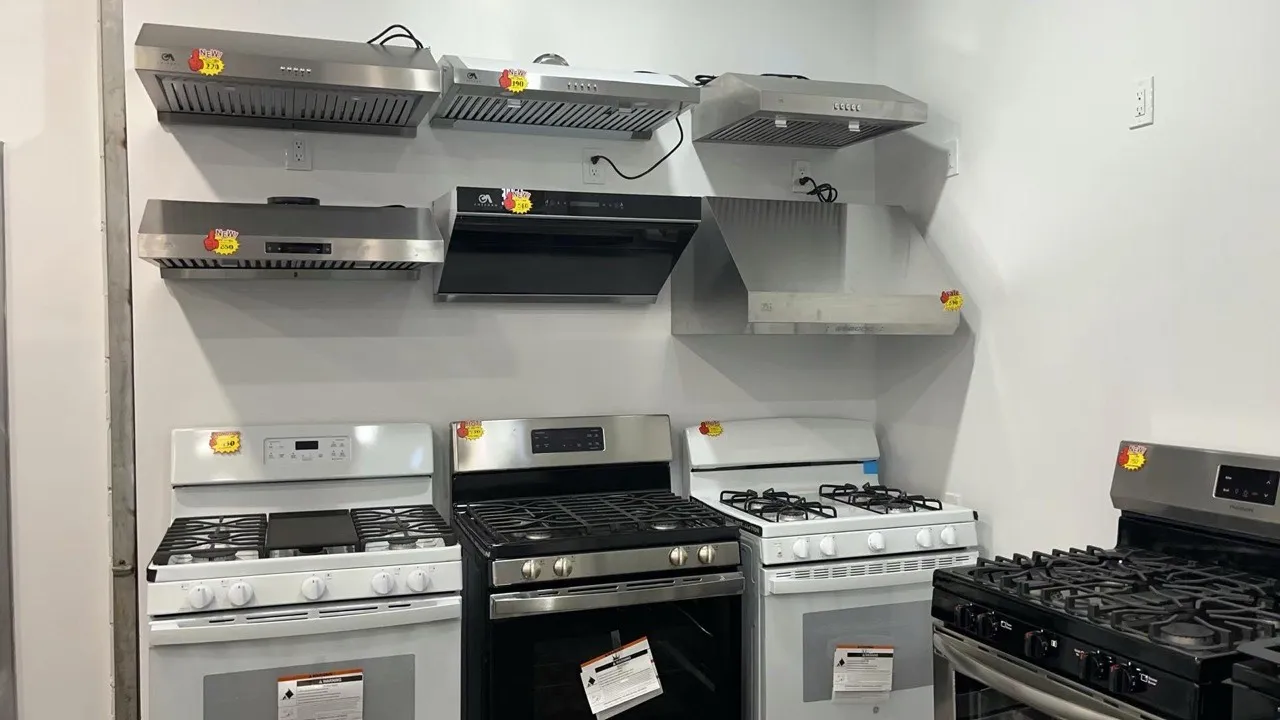 Stainless-steel range hoods and gas stoves on display in the Kings AC Supply Brooklyn showroom with sale tags